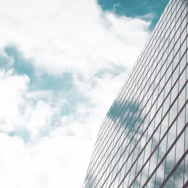 Glass tower facade reflecting cloud and sky